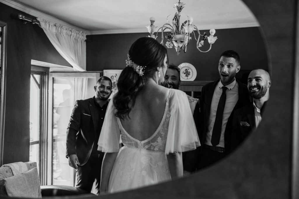 toronto wedding image of groomsmen smiling at bride in the mirror during bridal prep