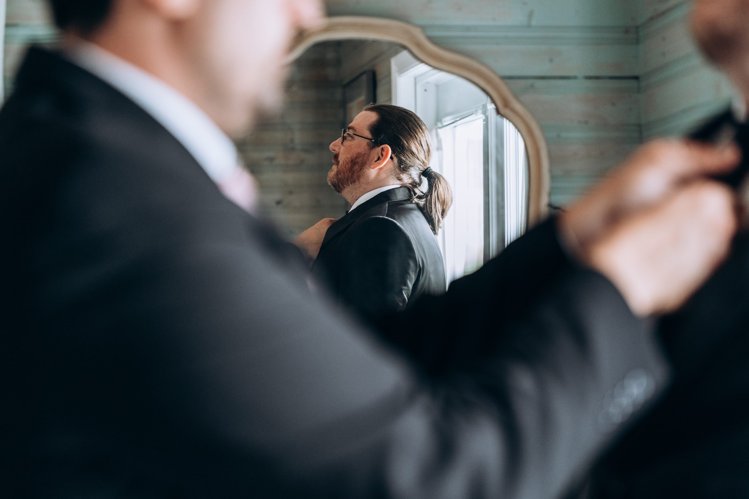 grooms reflection in a mirror as he prepares for his wedding day
