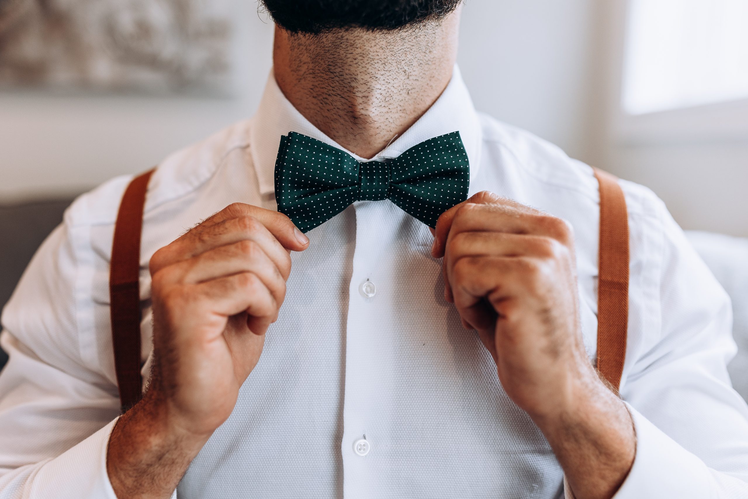 groom holding his bowtie prior to leaving for his wedding