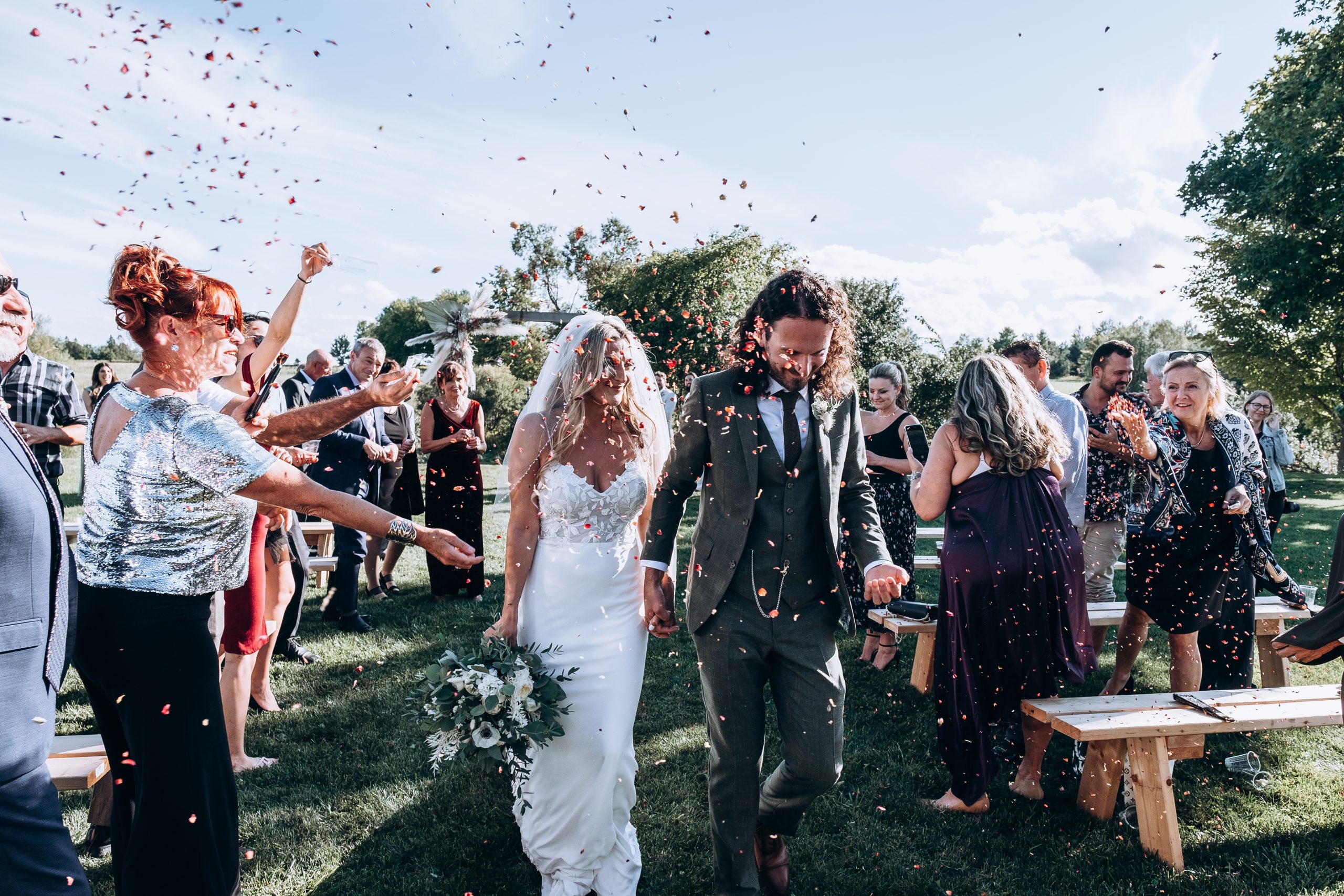 bride and groom hold hands as guests throw confetti after the ceremony
