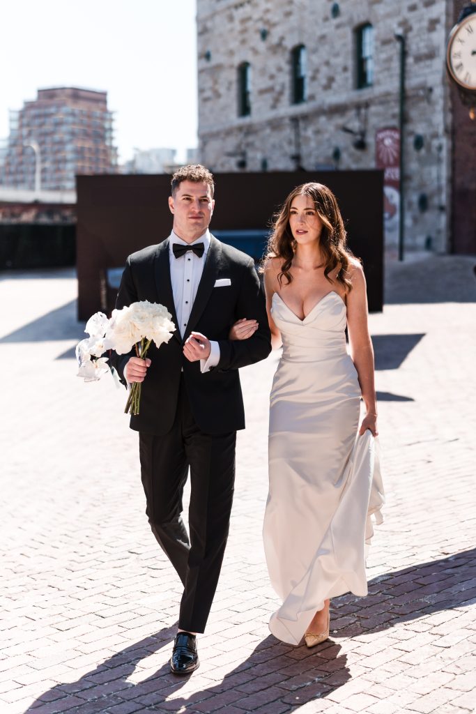 bride and groom stroll through the distillery district in toronto as they head to the wedding ceremony at archeo