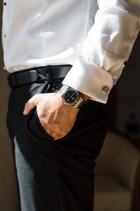 A person in a white dress shirt and black pants, styled for an event, stands indoors with sunlight illuminating their arm—a perfect shot for Wedding Photographers Toronto seeking elegant moments.